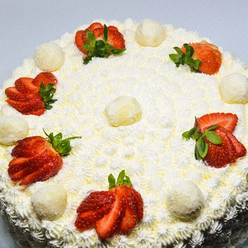Bolo decorado com chantilly, morangos frescos e bombons, visto de cima