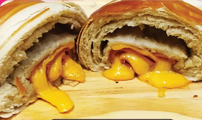 Croissant de presunto e queijo aberto com queijo cheddar derretido