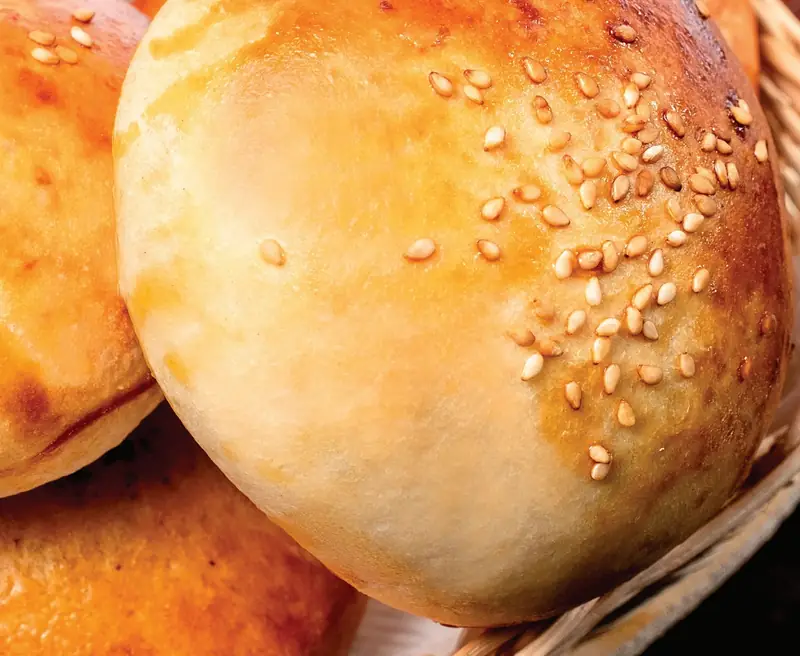 Pão de batata dourado com gergelim em cesta de vime