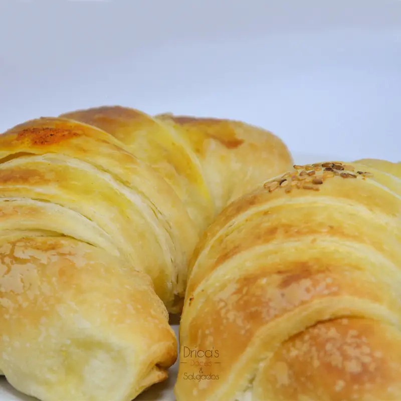 Dois croissants folhados dourados, com as camadas da massa aparentes