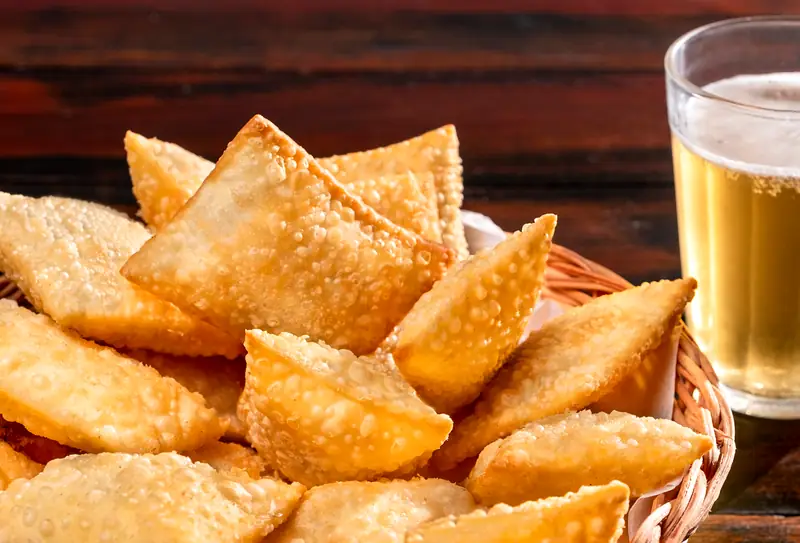 Pastéis crocantes servidos com copo de chope